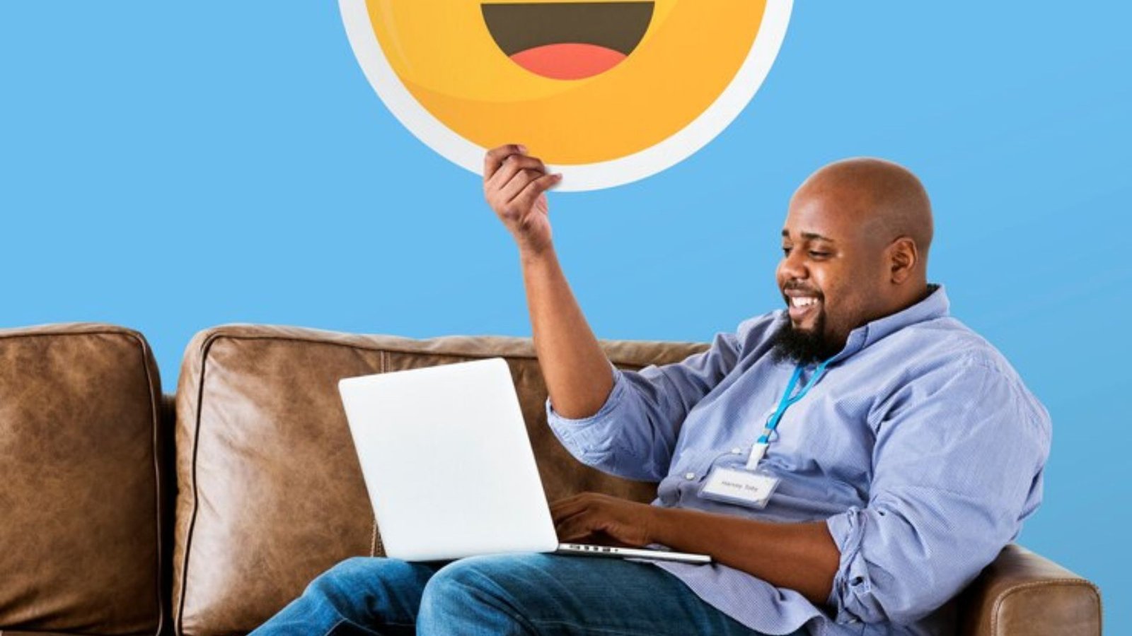 man showing heart eyes emoticon on couch with laptop on his lap